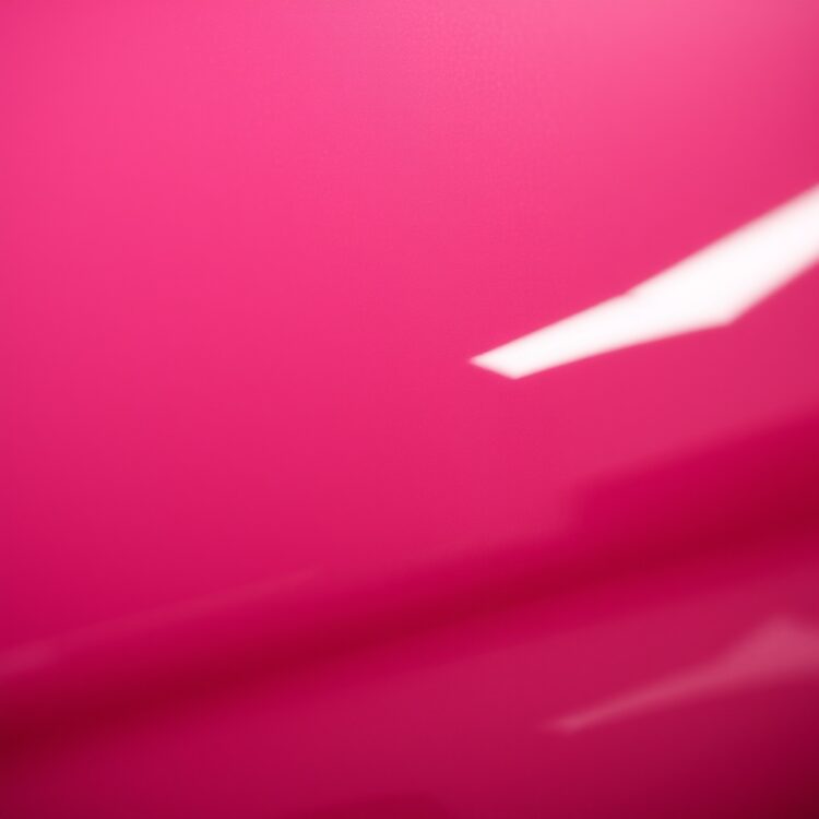 A close-up of a car's paint under bright lighting, focusing on the color's texture and shine, to visually debunk myths about car color affecting insurance rates.